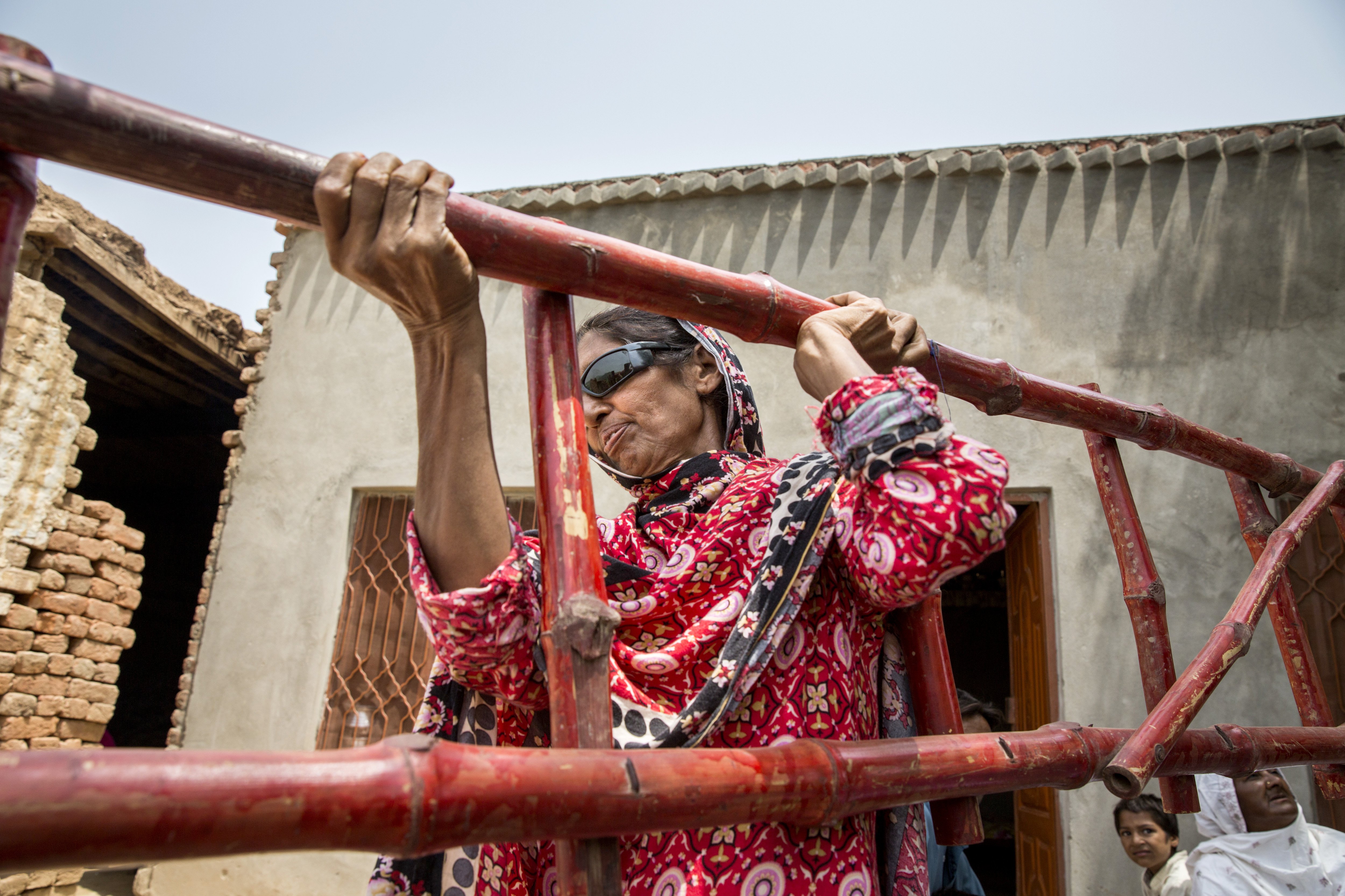 Kausar Shaheen lifts a ladder at her home in Manhiala, Chakwal District, Pakistan