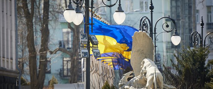 Statue in Kyiv with a Ukrainian flag in the background