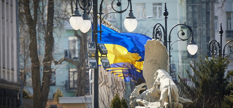 Statue in Kyiv with a Ukrainian flag in the background