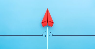 Red paper plane breaking through obstacle on blue background