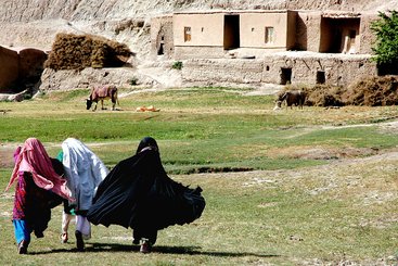 Three young women run across a field to their home in a remote part of Ghor Province, Central Afghanistan. 2022