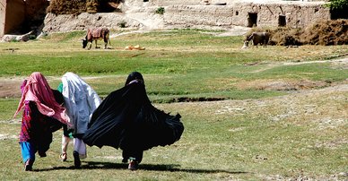 Three young women run across a field to their home in a remote part of Ghor Province, Central Afghanistan. 2022