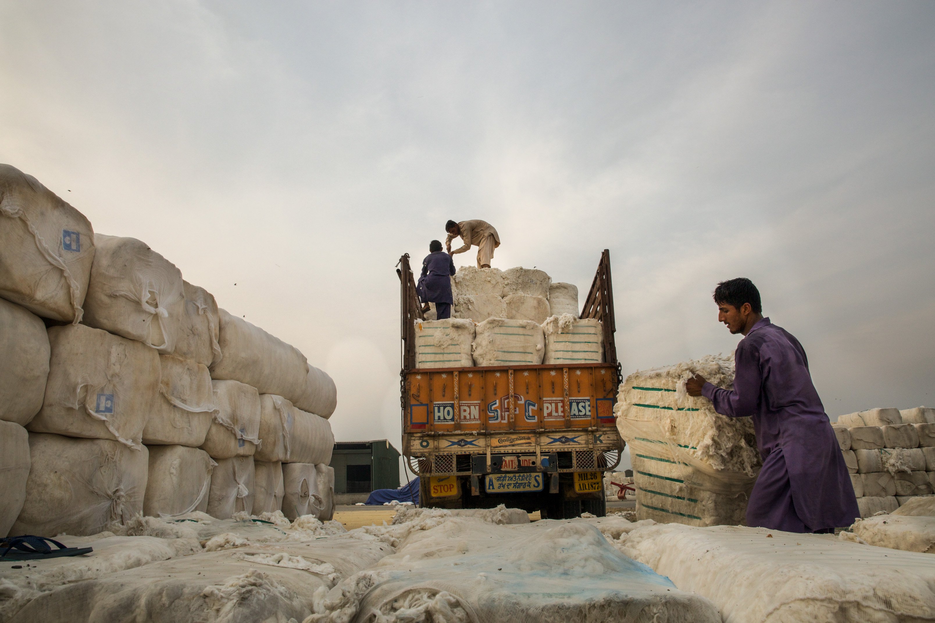 An Indian truck carrying cotton bales is being offloaded by the Pakistani workers at the Wagah-Attari Cargo Terminal