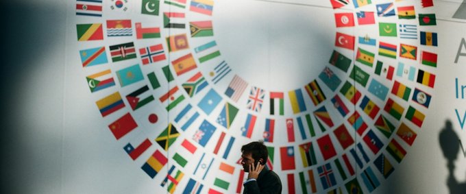 A person standing in front of a white wall decorated with flags of countries around the world.