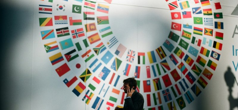A person standing in front of a white wall decorated with flags of countries around the world.