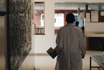 African doctor in white medical gown walking through the hospital lobby in village in Africa.